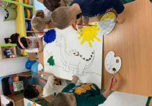 Dzieci z grupy 3 podczas wspólnego przygotowania pracy dinozaura